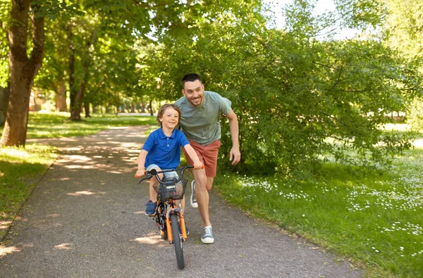 Vader leert kleine zoon fietsen in het park — Stockfoto