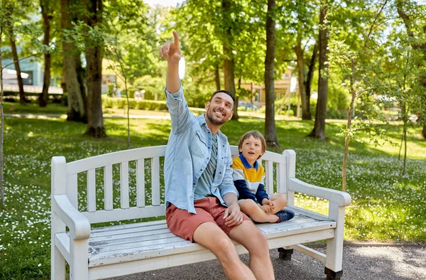 Otec ukazující něco synovi sedícímu na lavičce — Stock fotografie
