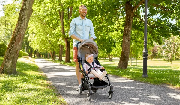 Šťastný otec s dítětem v kočárku v letním parku — Stock fotografie