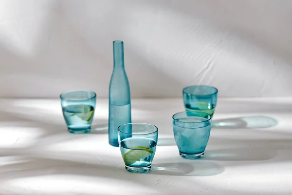 Poharak vízzel és citrommal fehér alapon — Stock Fotó