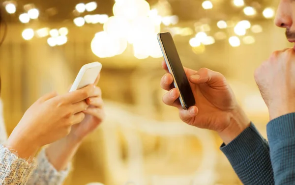 Primer plano de pareja con teléfonos inteligentes en la cafetería — Foto de Stock