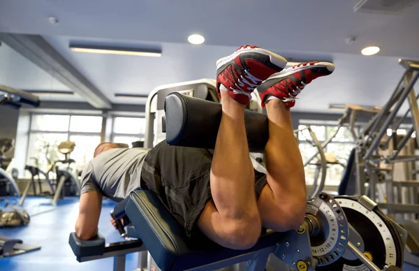 man flexing leg muscles on gym machine