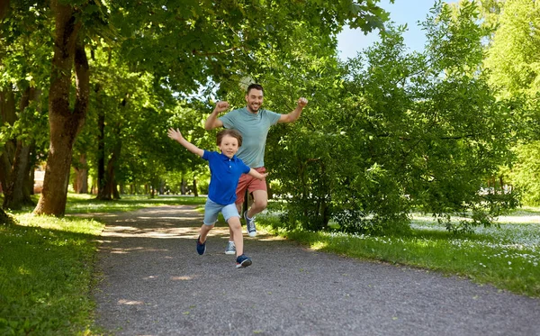 Šťastný otec a syn soutěžit v běhu v parku — Stock fotografie