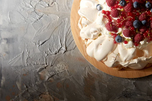 Bolo de merengue pavlova com bagas em tábua de madeira — Fotografia de Stock