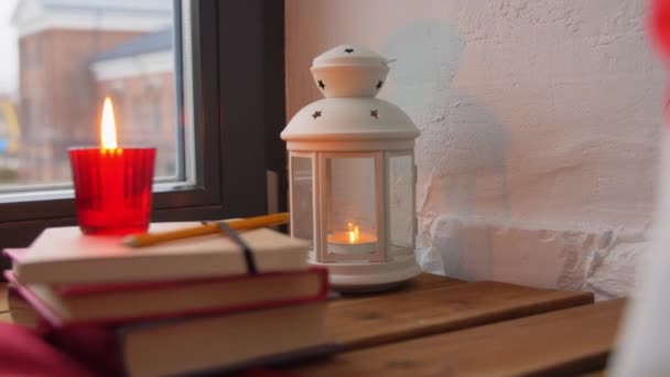 Vánoční věnec, knihy, svíčka, lucerna na okně — Stock video