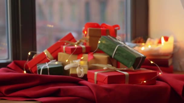 Karácsonyi ajándékok a piros abroszon az ablakpárkányon — Stock videók