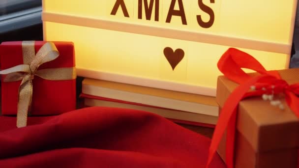 Frohe Weihnachten auf Leuchtkasten und Geschenke am Fenster — Stockvideo