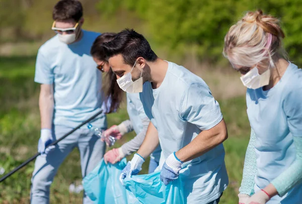 Voluntarios en máscaras con limpieza de basura en el parque —  Fotos de Stock