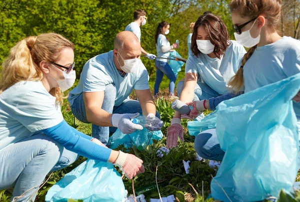 Vrijwilligers in maskers met schoonmaakafval in het park — Stockfoto