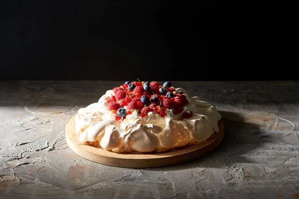 Bolo de merengue pavlova com bagas em tábua de madeira — Fotografia de Stock