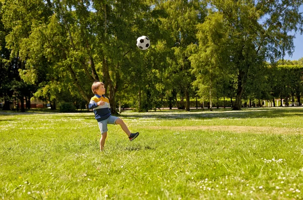 Niño feliz con pelota jugando al fútbol en el parque — Foto de Stock