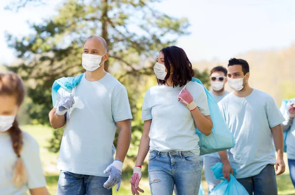 Wolontariusze w maskach z workami na śmieci w parku — Zdjęcie stockowe