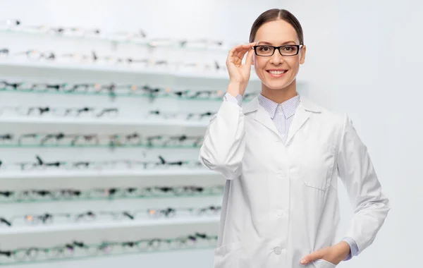 Doctora sonriente en gafas en tienda óptica —  Fotos de Stock