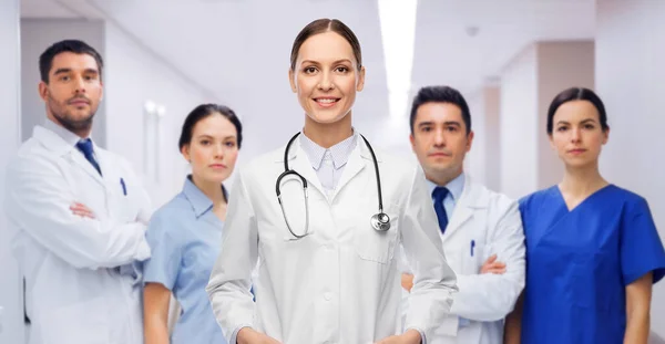 Glimlachende vrouwelijke arts met collega 's in het ziekenhuis — Stockfoto