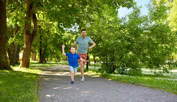 Gelukkig vader en zoon concurreren in hardlopen in park — Stockfoto