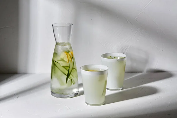 Vasos con agua de limón y pepino sobre la mesa —  Fotos de Stock