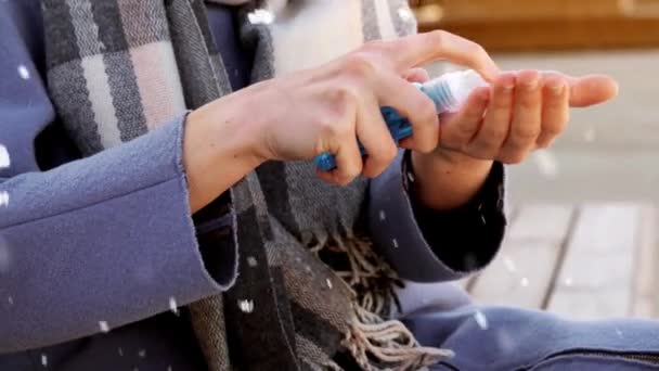 Maskeli kadın kış şehrinde el dezenfektanı kullanıyor. — Stok video