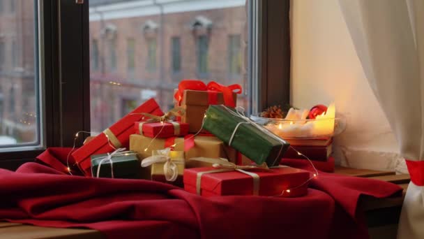 Χριστουγεννιάτικα δώρα στο κόκκινο τραπεζομάντιλο στο περβάζι του παραθύρου — Αρχείο Βίντεο