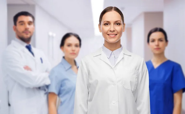 Smilende kvinnelig lege med kolleger på sykehus – stockfoto
