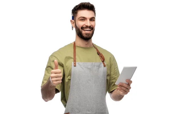 Uśmiechnięty kelner w fartuchu robi notatki do notatnika — Zdjęcie stockowe