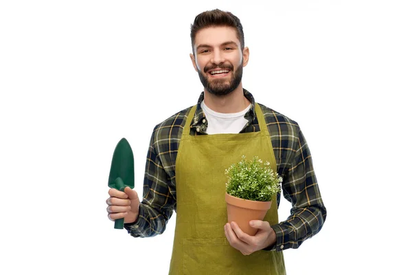 Счастливый садовник или фермер с лопатой и цветами — стоковое фото