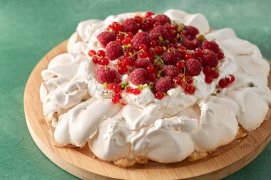 pavlova meringue cake with berries on wooden board clipart
