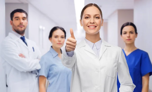 Doctor with colleagues shows thumbs up at hospital — Stok fotoğraf