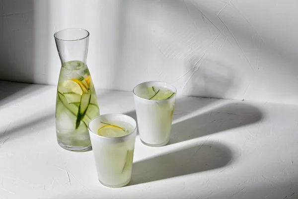 Bicchieri con acqua al limone e cetriolo sul tavolo — Foto Stock