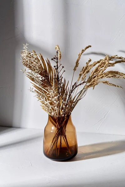 Flores secas decorativas em vaso de vidro marrom — Fotografia de Stock