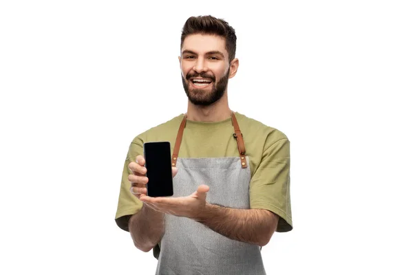 Feliz sorridente barman em avental mostrando smartphone — Fotografia de Stock