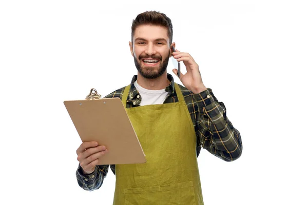 Male gardener with clipboard calling on smartphone — Stock Photo, Image