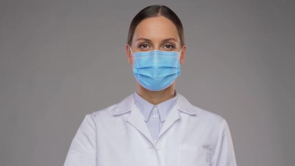 Kvinnlig läkare i medicinsk mask pekar finger uppåt — Stockvideo