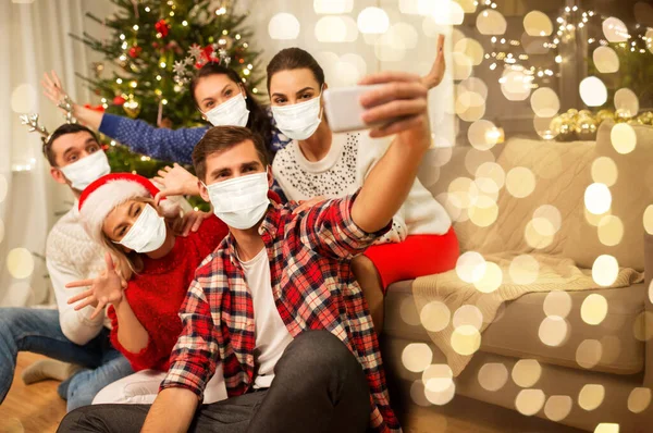 Amigos em máscaras tomando selfie na festa de Natal — Fotografia de Stock