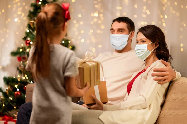 Família em máscaras com presentes de Natal em casa — Fotografia de Stock