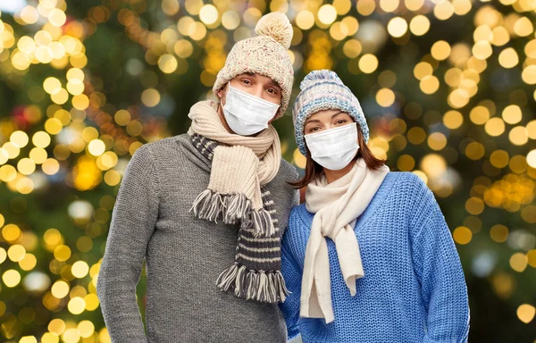 Casal em máscaras e roupas de inverno no Natal — Fotografia de Stock