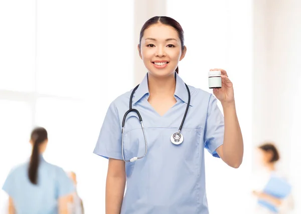 Glücklich asiatische Krankenschwester mit Medizin im Krankenhaus — Stockfoto