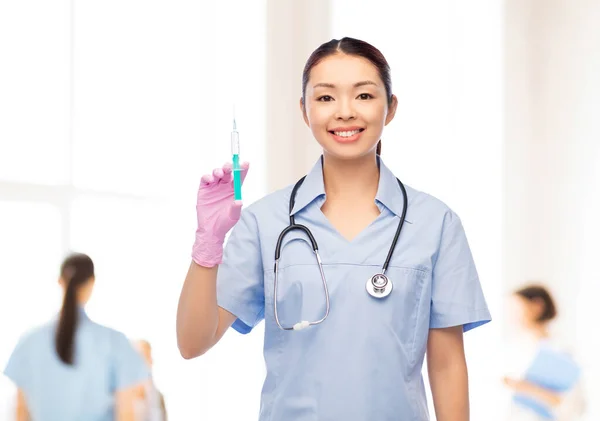Glücklich asiatische Krankenschwester mit Medizin und Spritze — Stockfoto