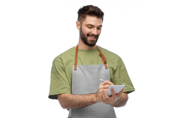 Smiling waiter in apron taking notes to notepad — Stock Photo, Image