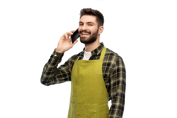 Gelukkig mannelijk tuinman in schort aanroepen op smartphone — Stockfoto