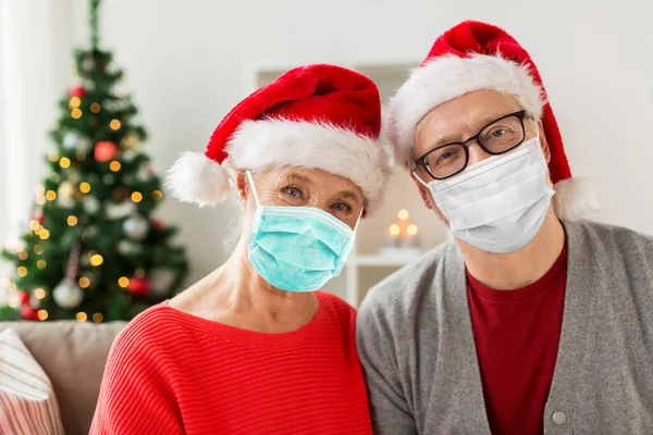 Casal de idosos em máscaras e chapéus de Papai Noel no Natal — Fotografia de Stock