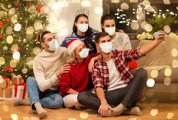 Friends in masks taking selfie at christmas party — Stock Photo, Image