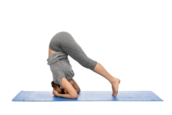 Vrouw maken yoga in headstand pose op mat — Stockfoto