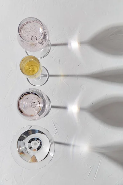 Copos de vinho deixando cair sombras na superfície branca — Fotografia de Stock