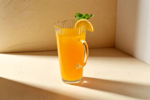 Jarra con zumo de naranja y menta en la mesa — Foto de Stock