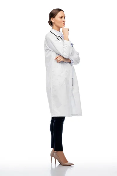 Думая женщина врач в белом халате — стоковое фото
