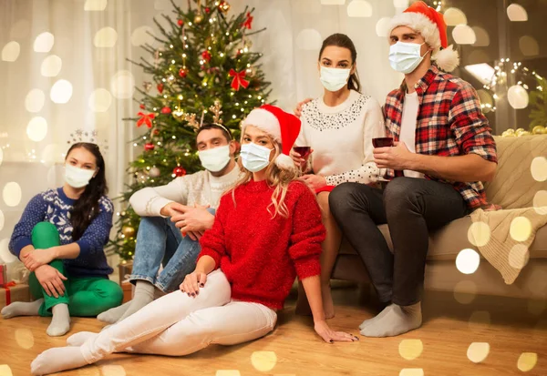 Friends in masks drinking wine on christmas — Stock Photo, Image