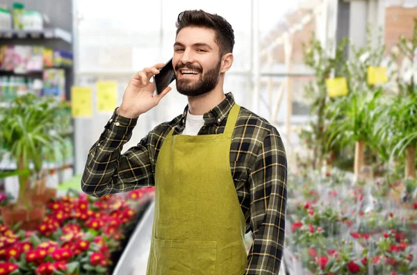 Mężczyzna ogrodnik dzwoni na smartfona w kwiaciarni — Zdjęcie stockowe