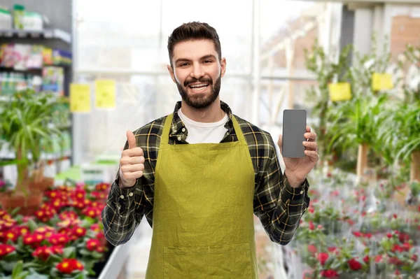 Vendedor con teléfono muestra pulgares hacia arriba en la tienda de flores — Foto de Stock