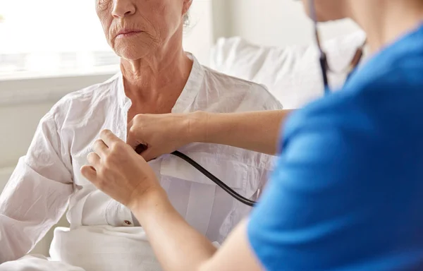 Médico com estetoscópio e mulher idosa no hospital — Fotografia de Stock