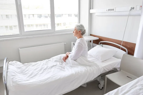 Anciana solitaria sentada en la cama en el hospital —  Fotos de Stock